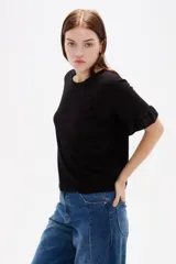 Remera negra de viscosa con textura acanalada, cuello redondo y mangas cortas terminadas en volados.