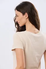 Remera beige de manga corta con cuello redondo, confeccionada en algodón con un diseño delantero que combina estampa floral y detalles bordados.