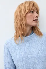 Sweater de punto con diseño de trenzas verticales, color rosa melange, de cuello redondo y manga larga con puños acanalados.