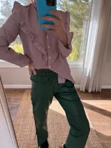 Pantalón slouchy de cuero ovino color verde inglés, corte mom fit con tiro semi alto y tajos inferiores.