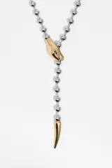 Collar de estilo lariat con cadena de bolas plateada y detalles dorados. Presenta un dije en forma de cabeza de serpiente que funciona como pasador y un terminal en punta que simula la cola. Está confeccionado principalmente en latón con acabado metálico bicolor.
