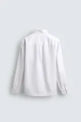 Camisa de corte regular fit confeccionada en tejido de algodón con diseño de rayas verticales. Presenta cuello abotonado, manga larga con puños abotonados, bolsillo plastrón en el pecho y cierre frontal con botones.