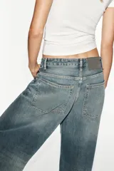 Jeans de tiro medio y corte baggy oversize con diseño de costuras marcadas en las piernas, trabillas para cinturón y cinco bolsillos tradicionales. Cierre frontal con cremallera y botón metálico.