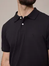 Remera polo negra de piqué de algodón con cuello clásico y tapeta de dos botones. Presenta un pequeño logo bordado en el pecho.