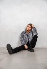 Campera puffer con estampado animal print en tonos gris y negro, cuello alto y cierre frontal.
