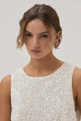 Top de lentejuelas color blanco, sin mangas y con espalda cruzada.
