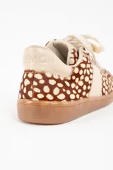 Zapatilla de cuero con textura de pelo y estampado animal print de puntos, con detalles en cuero liso color crema en los laterales y talón, y suela de goma color caramelo.