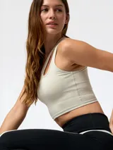 Top deportivo color blanco con diseño asimétrico de aberturas ovaladas en el escote, confeccionado en tejido con tecnología Aloe Vera.