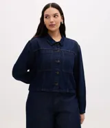 Campera cropped de jean color azul oscuro, con cuello camisero, cierre frontal de botones metálicos, bolsillos frontales grandes con solapa y mangas largas.
