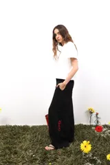 Pantalon de lino negro de corte amplio y tiro medio-bajo. Presenta bolsillos laterales y traseros, cierre con botón metálico y detalle de bordado en color rojo en la parte inferior de la pierna.
