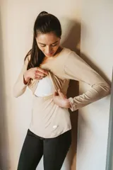 Remera color beige de algodón elastizado, con mangas largas y corte holgado. Cuenta con una abertura horizontal en el pecho para facilitar la lactancia.