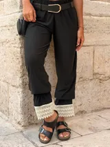 Pantalón negro de tiro alto con cintura elástica fruncida, corte holgado y detalle de puntilla blanca en los tobillos.