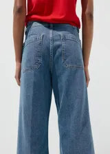 Jeans wide leg de tiro alto en tejido denim azul, con bolsillos de parche delanteros, trabillas para cinto y cierre frontal con cremallera y botón.