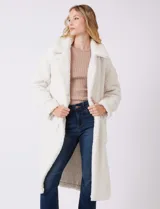 Tapado largo color blanco de tejido bouclé, marca Bcbg Maxazria. Cuenta con cuello de solapa amplia, cierre frontal con botones a presión internos, bolsillos funcionales y tajos laterales en el bajo. Forro interno a tono.