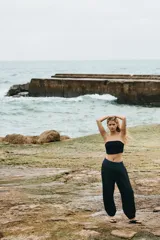 Pantalón negro de corte holgado en tejido de punto con efecto arrugado. Presenta una cintura ancha fruncida con elástico oculto y piernas globo con bajos elásticos.