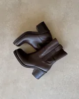 Botín corto de cuero color marrón oscuro, con punta cuadrada y taco ancho acanalado.