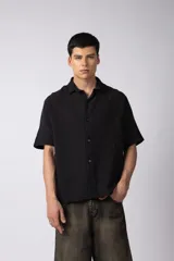 Camisa de manga corta confeccionada en lino, con cuello clásico y cierre frontal de botones. Presenta un diseño de corte relajado y textura aireada, con una estampa trasera que reinterpreta símbolos andinos en clave urbana.