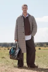 Trench de corte relajado con estampado de cuadros en tonos beige y marrón, cuello solapa en piel marrón, manga larga, bolsillos de vivo en cadera, cinturón ajustable y cierre frontal con botones.