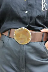 Cinto de cuero azul con hebilla circular de piedra ágata con borde dorado.