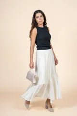Falda larga color crudo, de silueta amplia con volado en el ruedo y cintura elástica.