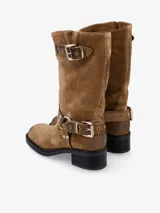 Bota de caña media de cuero negro, estilo biker, con caña arrugada y detalles de correas con hebillas metálicas plateadas en la parte superior y alrededor del tobillo. Posee un taco bajo y grueso.