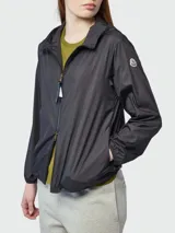 Campera rompevientos Moncler modelo Enette, color negro, con capucha, cierre frontal y puños elásticos. Presenta el logo de la marca aplicado en la manga izquierda.