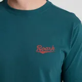 Remera verde con logo Roark bordado en rojo en el pecho.
