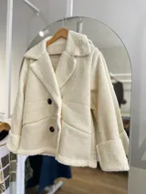 Chaqueta negra con forro tipo corderito, doble botonadura y cuello solapa.