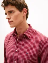Camisa de corte regular de Tommy Hilfiger, confeccionada en popelín de puro algodón con acabado aterciopelado y diseño de cuadros en tonos rojos y blancos. Presenta cuello clásico abotonado, mangas largas con puños redondeados y el logo bordado en el pecho.