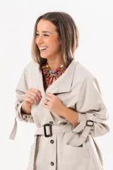 Trench de gabardina Tencel color beige, de silueta relajada, con cierre frontal de botones, lazo desmontable y regulable en la cintura, bolsillos amplios y lazos en los puños.