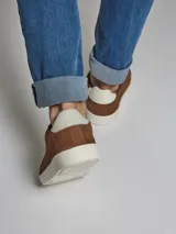 Zapatillas acordonadas de cuero nobuck color marrón con diseño calado y suela blanca de goma.