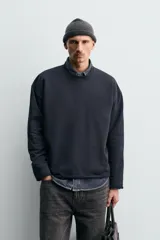 Sudadera de corte relajado confeccionada en algodón compacto con interior de rizo. Presenta cuello redondo acabado en rib, manga larga y bordes irregulares enrollados.
