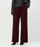 Pantalón de corte wide leg confeccionado en crepé color bordó, con cintura alta, cierre frontal con cremallera y detalle de hebilla ajustable en la cintura.