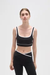 Top deportivo negro con detalles de ribete blanco en el escote y breteles. Presenta un diseño de corte cuadrado y ajuste al cuerpo.