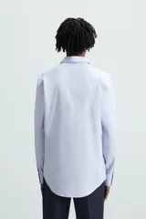 Camisa de corte regular fit en color celeste, con cuello italiano, manga larga con puños abotonados y cierre frontal de botones.