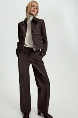 Pantalón de tiro medio en denim oscuro con costuras a contraste. Presenta corte recto, bolsillos delanteros, trabillas en la cintura y cierre frontal con cremallera y ganchos metálicos.