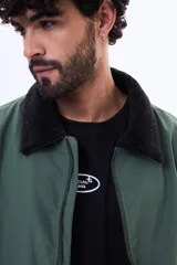 Campera de nylon color negro con cierre frontal, puños y ruedo elásticos, y cuello con forro de corderito sintético.