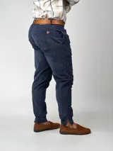 Pantalón de pana negro de corte recto, con bolsillos laterales y traseros. Se ajusta a la cintura con cinturón de cuero negro.