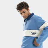 Buzo estilo rugby de manga larga, con cuello camisero en contraste de color azul oscuro. Presenta una franja horizontal ancha en color crema en el pecho con el logo de la marca bordado, y cuerpo en color azul claro.