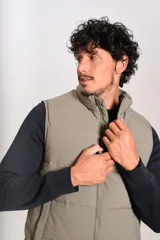 Chaleco puffer de corte regular, color beige, con cierre frontal y cuello alto. Presenta un diseño acolchado horizontal y logo bordado en el pecho.