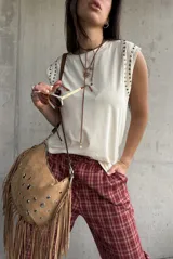 Remera sin mangas de color manteca, con detalle de tachas metálicas doradas en los hombros.