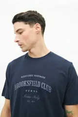 Remera clásica de manga corta color azul marino, con estampado frontal del logo "Brooksfield Club" en gris claro.