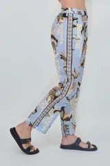 Pantalón celeste de corte recto y tiro alto, confeccionado en mezcla de lino y algodón, con estampado selvático que incluye tigres y hojas en tonos marrones y beige.