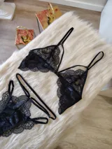Conjunto de lencería de encaje negro compuesto por un bralette con detalle de aro central y una tanga de doble tira regulable estilo less.
