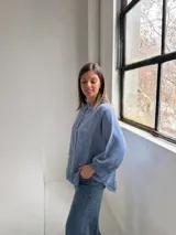 Camisa azul de lino con cuello mao, cierre frontal con botones y mangas largas abullonadas con puños elásticos.