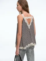 Top de tirantes con diseño a rayas horizontales en blanco y negro, confeccionado con terminaciones de encaje en el escote y en el ruedo.