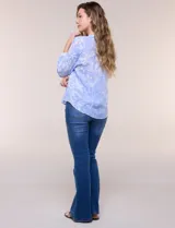 Blusa celeste con estampado efecto pincelada blanca, de corte semi holgado, escote en V con cuello solapa y media abotonadura frontal con botones nacarados. Presenta finas alforzas verticales en la pechera y mangas 3/4 con puños elastizados.