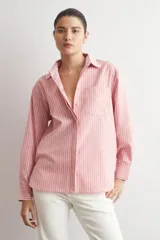 Camisa de corte oversized con estampado de rayas verticales, cuello clásico, cierre frontal con botones y bolsillo en el pecho.