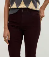 Pantalón slim de jean marrón, de cintura mediana con cierre frontal de cremallera y botón, bolsillos y trabillas para cinturón.