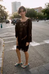 Vestido corto de algodón color marrón, con escote redondo y mangas tres cuartos. Presenta detalles de bordados a tono y aplicaciones de tejido perforado calado en toda la prenda.